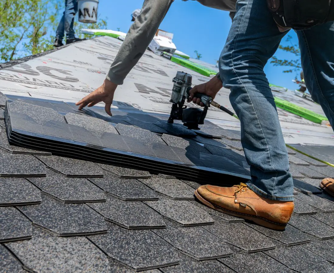 Roofer working on residential shingle roof — homeowner insurance claims, Ave Maria Law Center